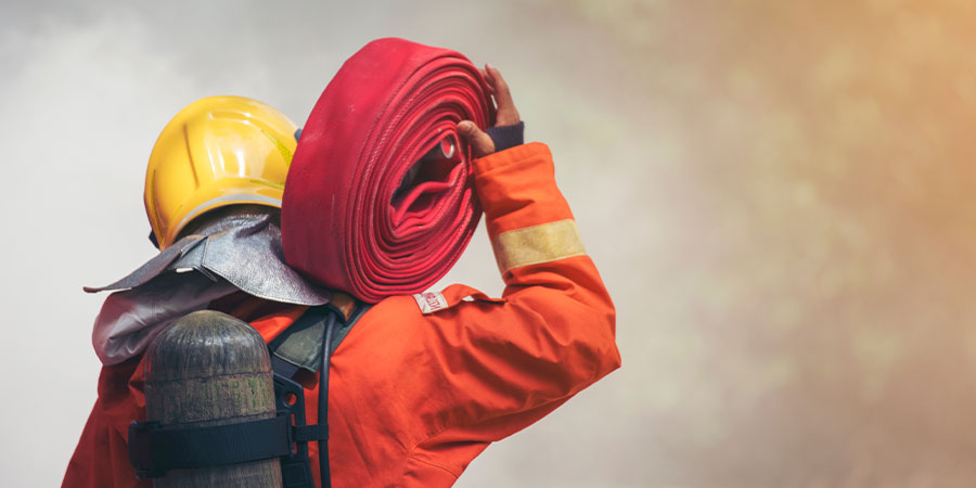  Feuerwehrkraft mit Ausrüstung, einen Löschschlauch tragend