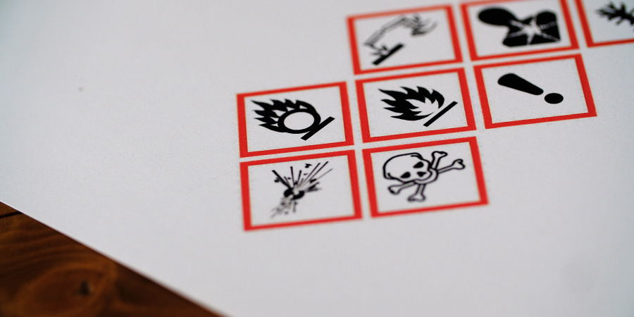 Blatt Papier auf einem Tisch mit Gefahrsymbolen