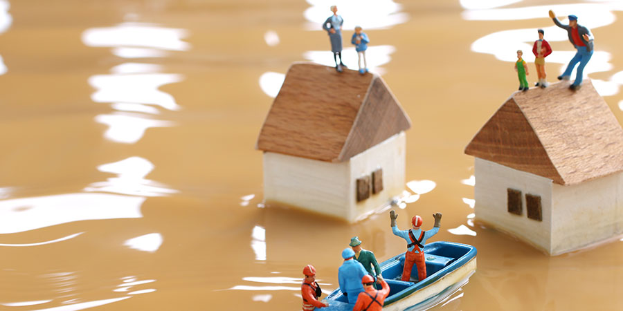 Diorama mit Häusern bei Hochwasser und Menschen, die auf Rettung warten und Helfern