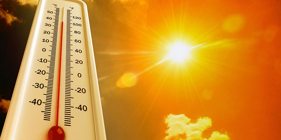 Ein Thermometer vor einem orange gefärbten Sommerhimmel mit strahlender Sonne
