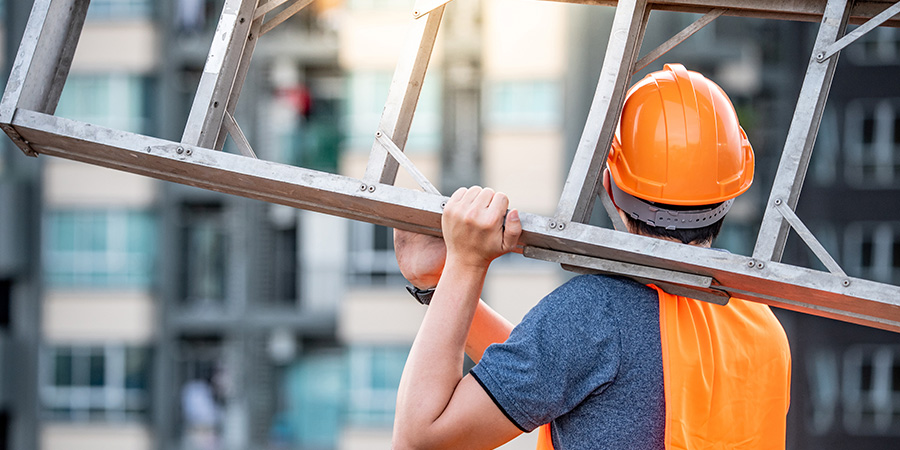 Arbeiter mit Leiter auf dem Rücken